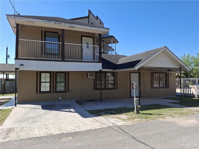 front of property featuring a balcony, fence, and a shingled roof