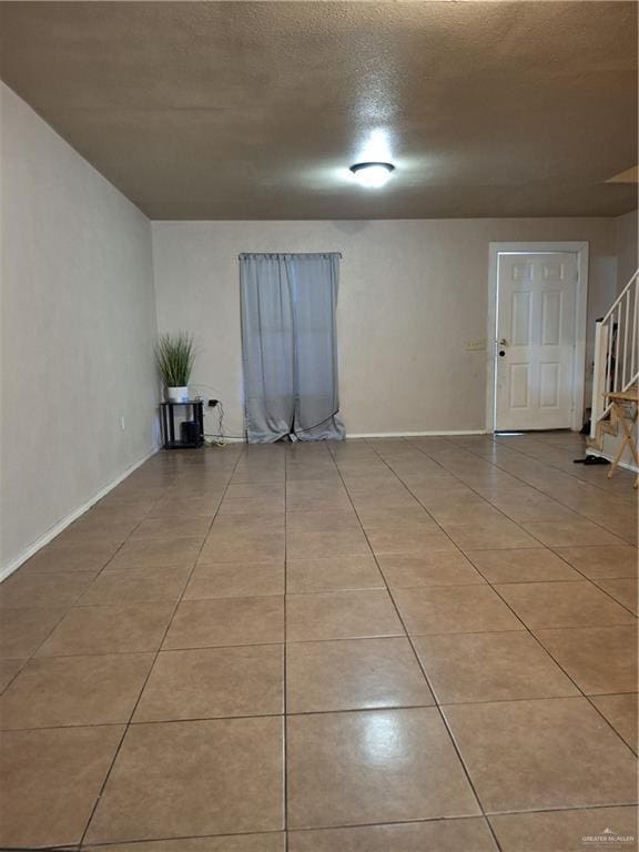 spare room featuring baseboards, stairway, and light tile patterned flooring
