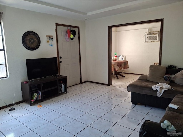 living area featuring light tile patterned floors, baseboards, and a wall unit AC