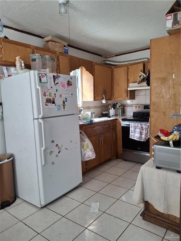 kitchen featuring light countertops, freestanding refrigerator, electric range, a textured ceiling, and brown cabinets