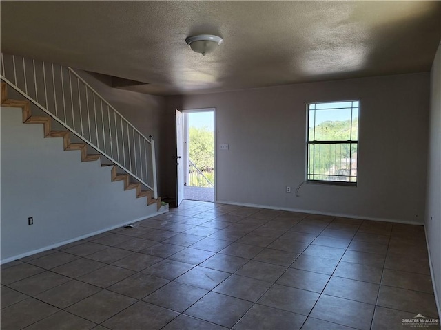 entryway featuring baseboards, stairs, tile patterned flooring, and a textured ceiling