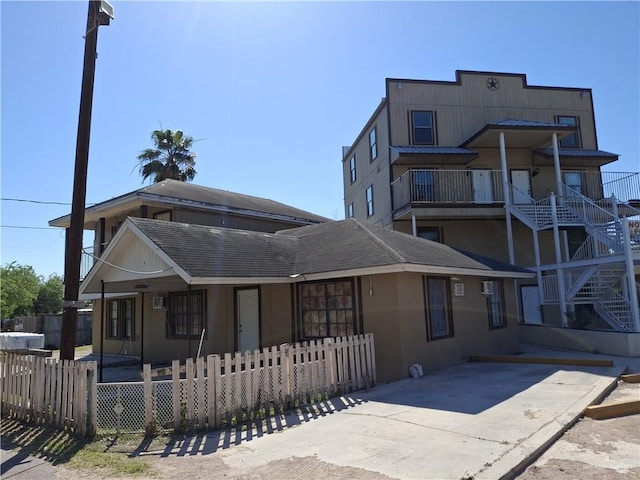 exterior space with stairway, covered porch, stucco siding, and a fenced front yard