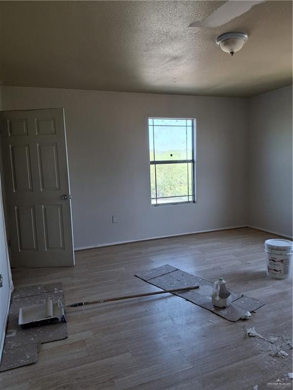 empty room featuring baseboards, wood finished floors, and a textured ceiling