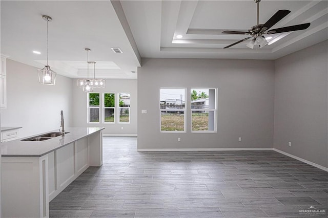 kitchen featuring a tray ceiling, visible vents, hanging light fixtures, open floor plan, and white cabinetry