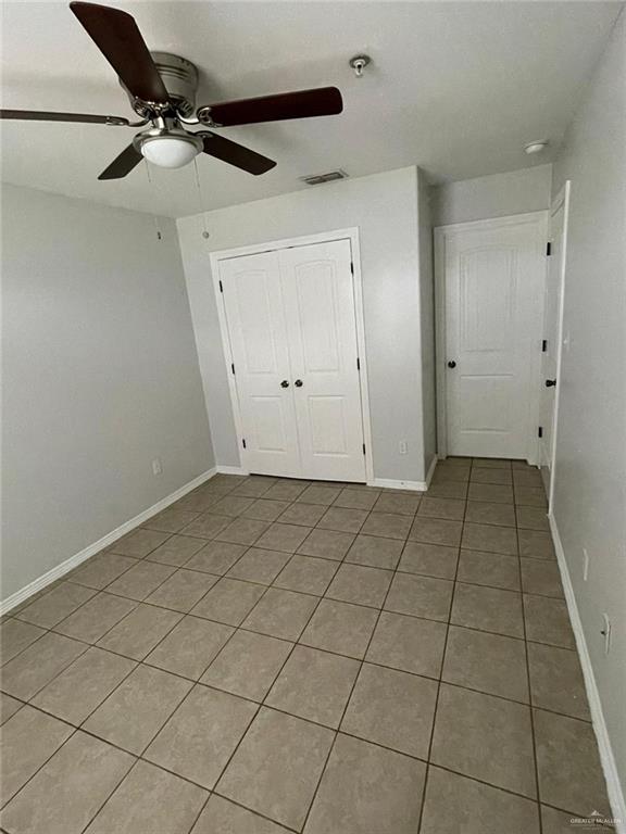 unfurnished bedroom featuring ceiling fan, light tile patterned floors, and a closet