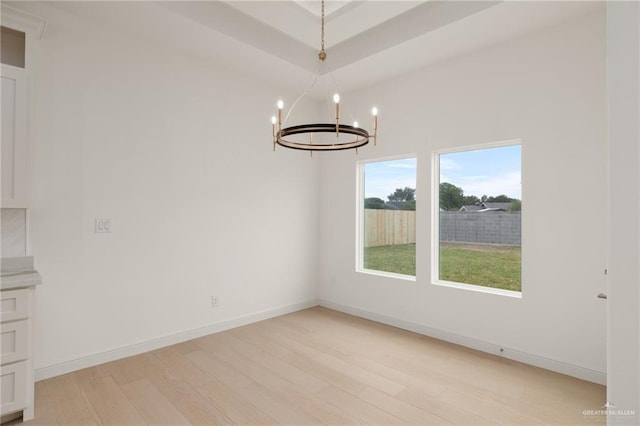 unfurnished dining area featuring baseboards, light wood finished floors, and a chandelier