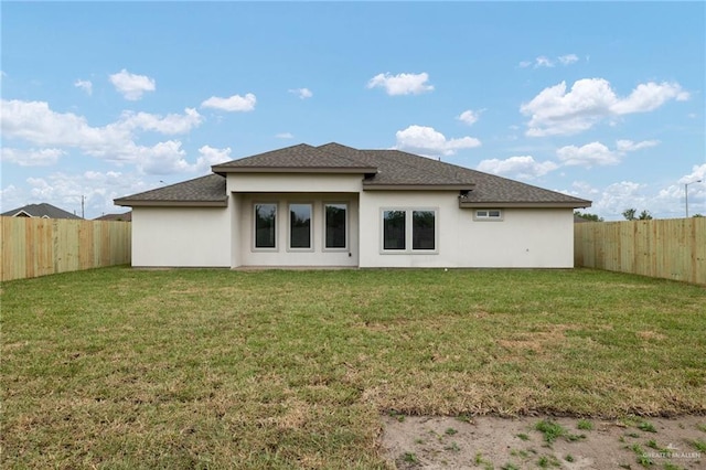 back of house with a fenced backyard, a yard, and a shingled roof