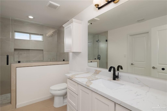 full bath featuring vanity, a stall shower, toilet, and visible vents