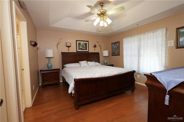 bedroom featuring a tray ceiling, ceiling fan, and dark hardwood / wood-style floors