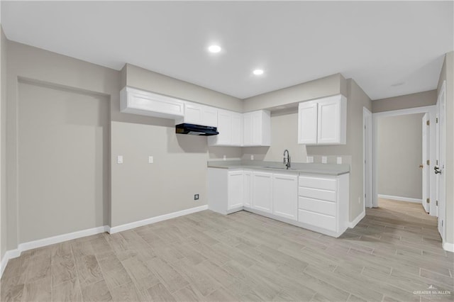 kitchen with white cabinetry, extractor fan, light hardwood / wood-style floors, and sink