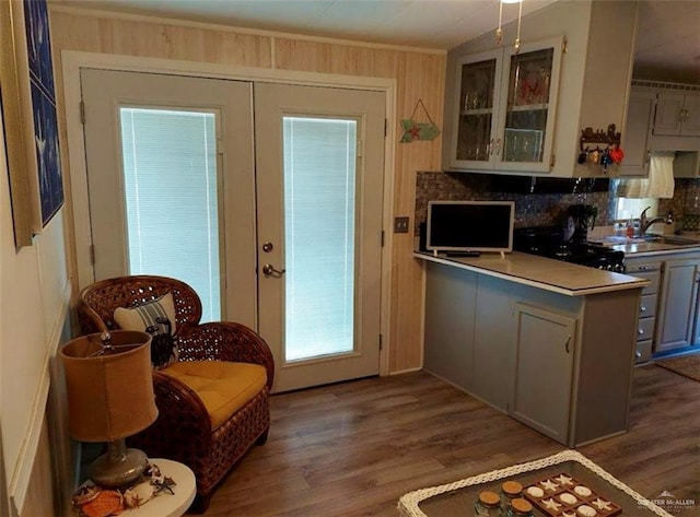 kitchen featuring black stove, sink, tasteful backsplash, kitchen peninsula, and light hardwood / wood-style floors