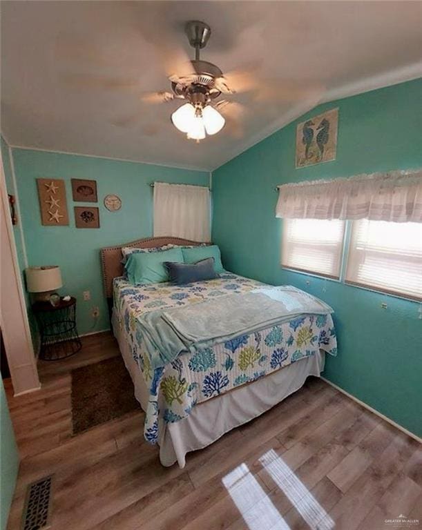 bedroom featuring ceiling fan, hardwood / wood-style floors, and vaulted ceiling