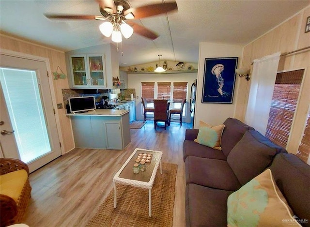 living room with light wood-type flooring, ceiling fan, and lofted ceiling