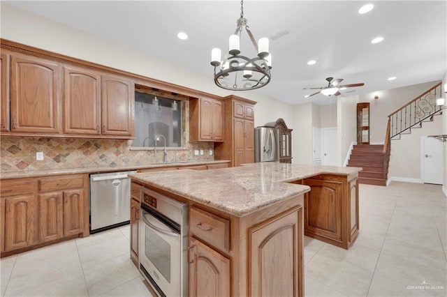 kitchen with decorative light fixtures, a kitchen island, ceiling fan with notable chandelier, and appliances with stainless steel finishes