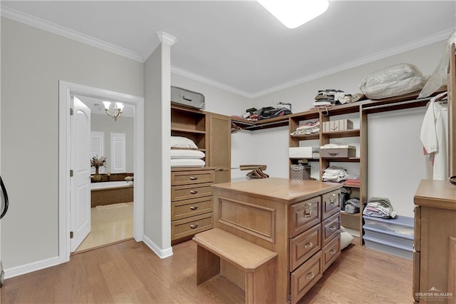 walk in closet with light hardwood / wood-style floors and a notable chandelier