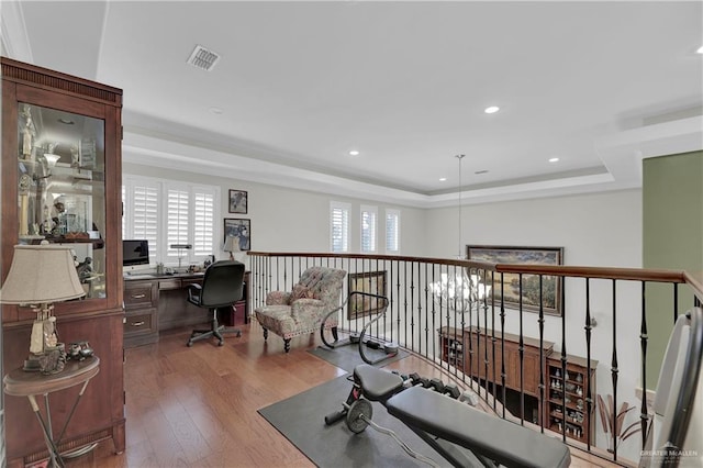 exercise area featuring wood-type flooring and a tray ceiling