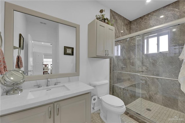 bathroom featuring tile patterned floors, vanity, toilet, and a shower with shower door