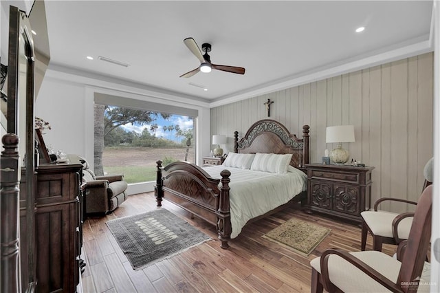 bedroom with ceiling fan, hardwood / wood-style floors, and wooden walls