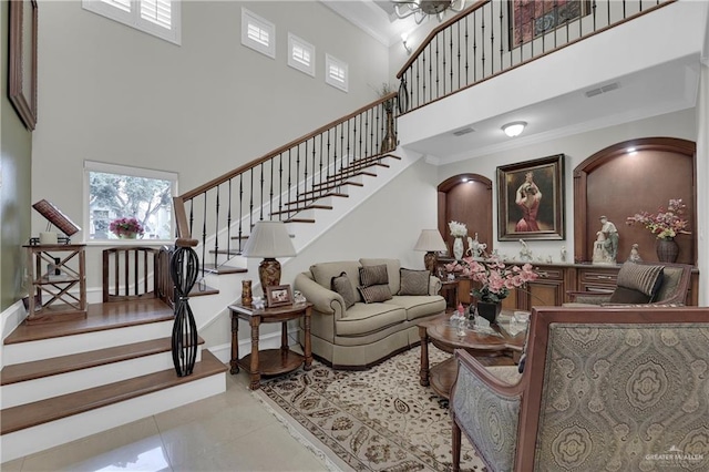 living room with crown molding, a towering ceiling, and light tile patterned floors