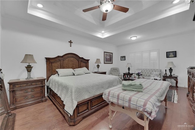 bedroom featuring a raised ceiling, ceiling fan, crown molding, and light wood-type flooring