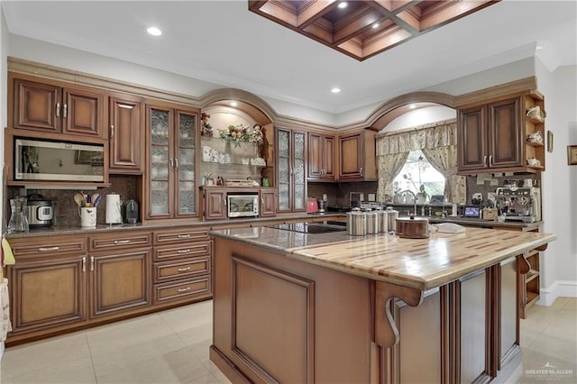 kitchen featuring a center island, coffered ceiling, wooden counters, decorative backsplash, and ornamental molding