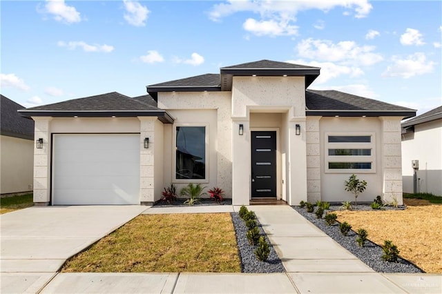 prairie-style home with a front lawn, roof with shingles, stucco siding, concrete driveway, and an attached garage