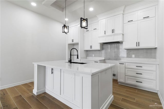 kitchen with a sink, dark wood finished floors, premium range hood, decorative backsplash, and a center island with sink