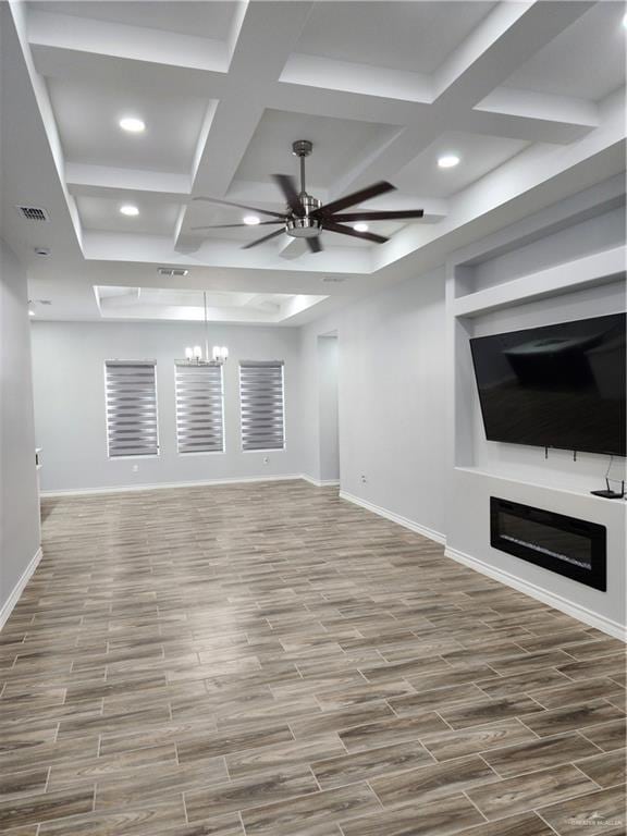 unfurnished living room featuring beam ceiling, ceiling fan with notable chandelier, hardwood / wood-style flooring, and coffered ceiling