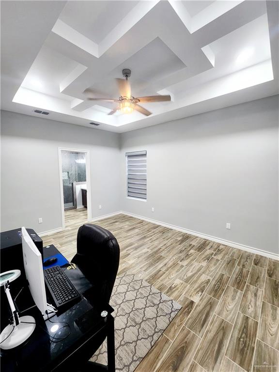 office featuring hardwood / wood-style floors, ceiling fan, and a tray ceiling