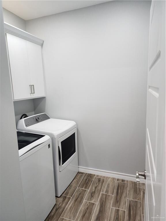 laundry area featuring cabinets, dark hardwood / wood-style flooring, and washer and clothes dryer