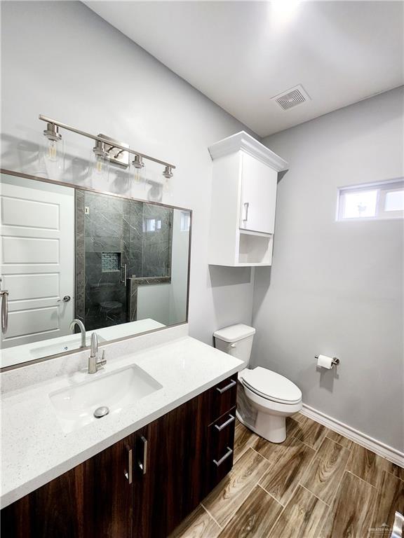 bathroom featuring vanity, toilet, and a shower with door