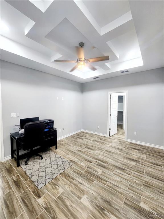 home office with a tray ceiling, ceiling fan, and hardwood / wood-style flooring