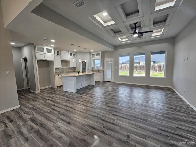 kitchen featuring a center island, dark wood-type flooring, coffered ceiling, white cabinets, and hanging light fixtures