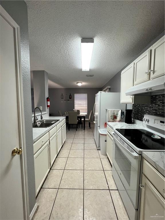 1414 Vatia Blvd, Mission, TX 78572 - kitchen featuring white electric stove, under cabinet range hood, light countertops, a textured ceiling, and light tile patterned floors
