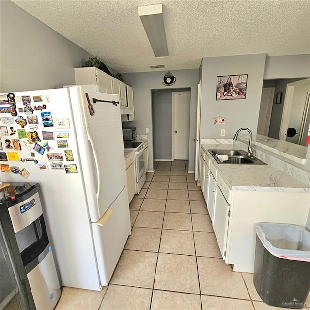 1414 Vatia Blvd, Mission, TX 78572 - kitchen featuring white appliances, white cabinets, light tile patterned floors, a textured ceiling, and a peninsula