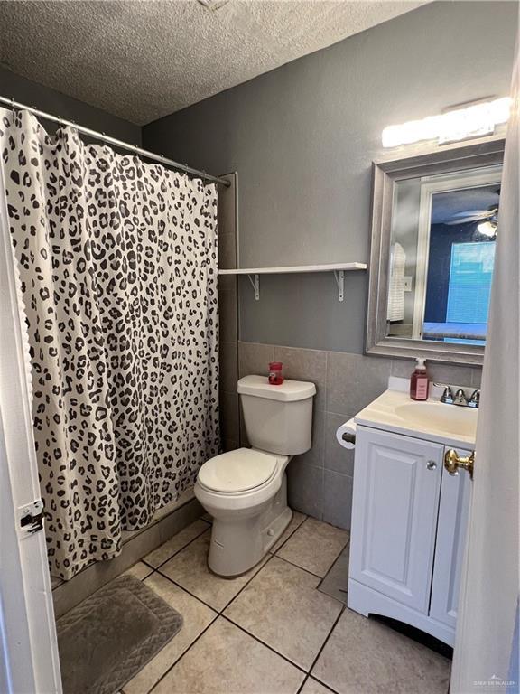 1414 Vatia Blvd, Mission, TX 78572 - bathroom featuring tile walls, a textured ceiling, vanity, tile patterned floors, and curtained shower