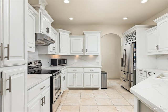 kitchen featuring white cabinets, decorative backsplash, light stone countertops, light tile patterned floors, and appliances with stainless steel finishes