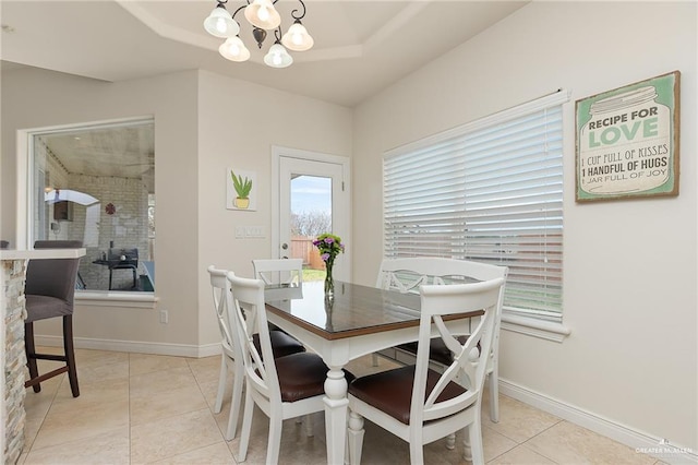 dining space featuring a chandelier, a tray ceiling, and light tile patterned flooring