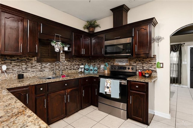 kitchen with appliances with stainless steel finishes, tasteful backsplash, sink, light stone countertops, and dark brown cabinets