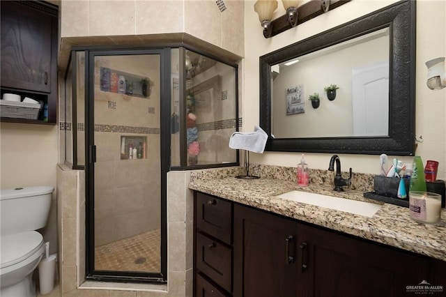 bathroom featuring vanity, toilet, and a shower with shower door