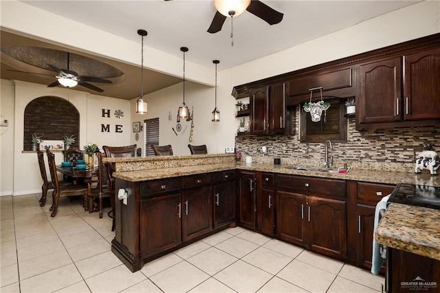 kitchen with light stone counters, decorative light fixtures, sink, and tasteful backsplash