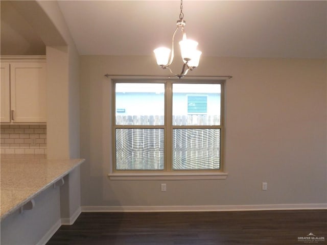 unfurnished dining area with baseboards, dark wood-type flooring, and an inviting chandelier