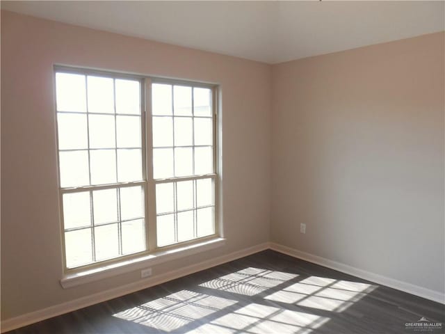 spare room featuring baseboards and dark wood finished floors