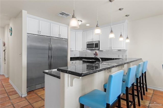 301 Houston Ave, Port Isabel, TX 78578 - kitchen with appliances with stainless steel finishes, tasteful backsplash, a peninsula, white cabinetry, and hanging light fixtures
