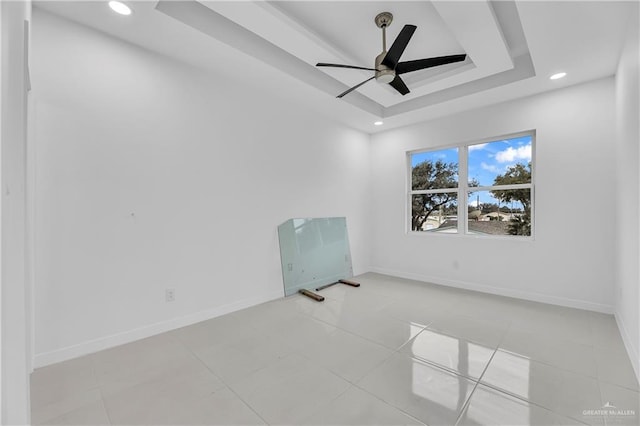 tiled spare room with a raised ceiling and ceiling fan