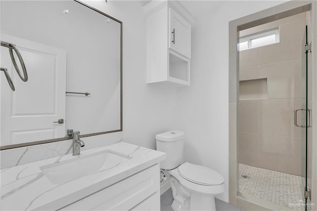 bathroom with toilet, an enclosed shower, and vanity