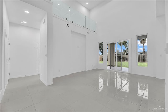 tiled spare room with a high ceiling and a healthy amount of sunlight