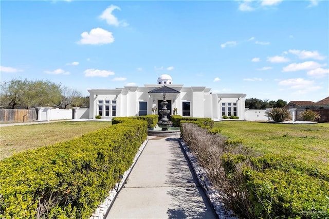 view of front of property with fence, a front lawn, and stucco siding