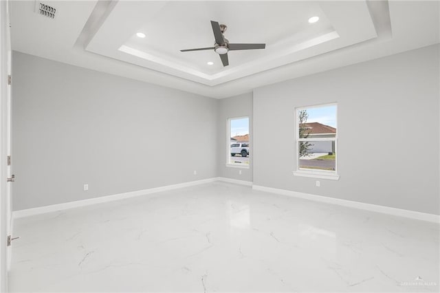 unfurnished room featuring a raised ceiling and ceiling fan