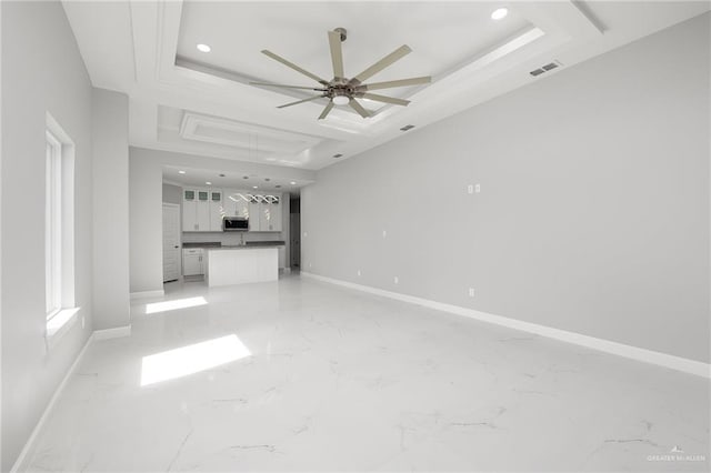 unfurnished living room with a raised ceiling and ceiling fan